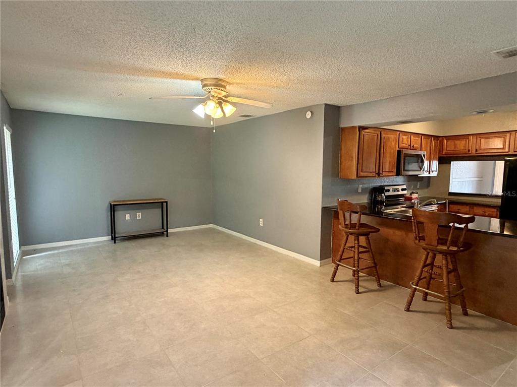 A dining area with tile floors and a ceiling fan opens to a kitchen counter — 564 BRECKENRIDGE VILLAGE UNIT 106, ALTAMONTE SPRINGS, FL