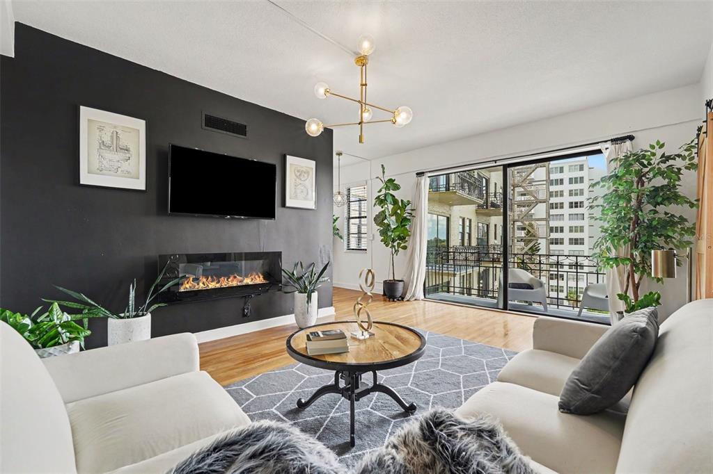A living room features a black accent wall with a fireplace, television, and balcony access — 2109 BAYSHORE BOULEVARD UNIT 609, TAMPA, FL