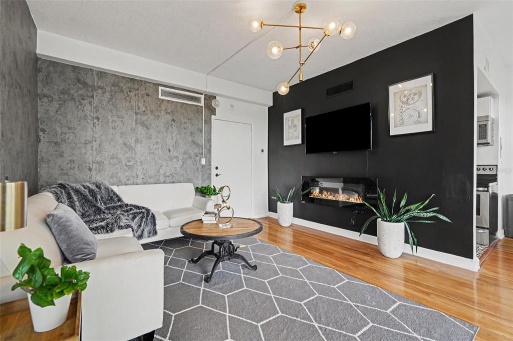 A living room features a black accent wall with a fireplace, television, and concrete wall — 2109 BAYSHORE BOULEVARD UNIT 609, TAMPA, FL
