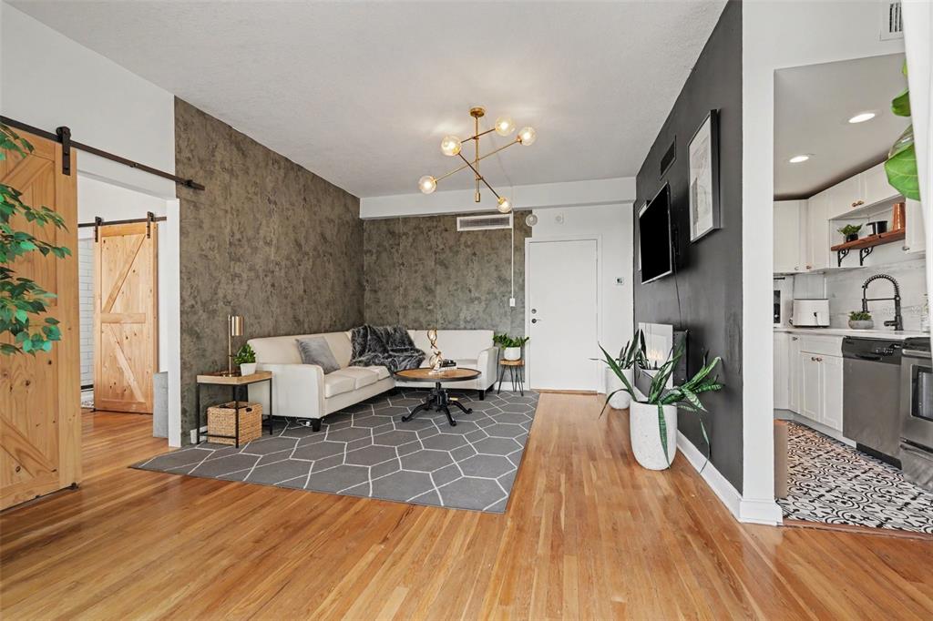 A living room features a textured accent wall, a sectional sofa, and a barn door — 2109 BAYSHORE BOULEVARD UNIT 609, TAMPA, FL