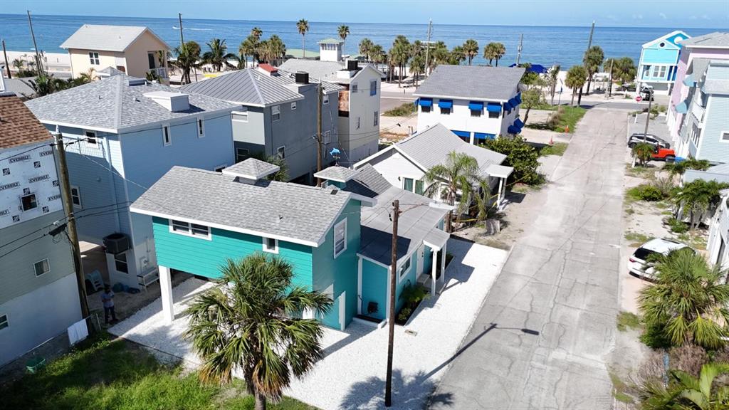 An elevated teal house sits near a beach with other coastal homes and a street — 37 80TH TERRACE, TREASURE ISLAND, FL