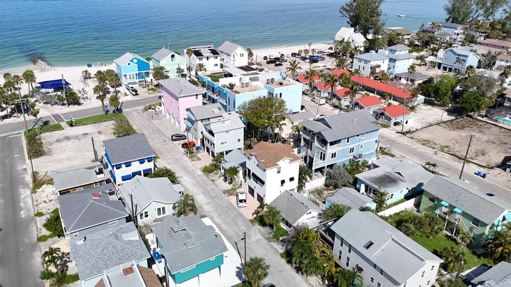 An aerial view shows a coastal neighborhood with colorful houses near a sandy beach — 37 80TH TERRACE, TREASURE ISLAND, FL