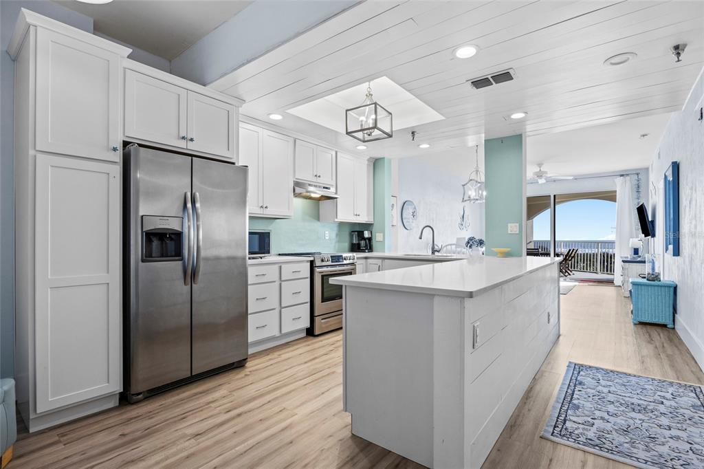 A white kitchen with stainless steel appliances, a center island, and light wood flooring — 104 SURFVIEW DRIVE UNIT 2203, PALM COAST, FL