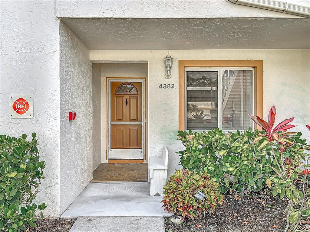 The exterior entrance features a brown door, a white bench, and a window with blinds — 4382 MADEIRA COURT UNIT 3361, SARASOTA, FL