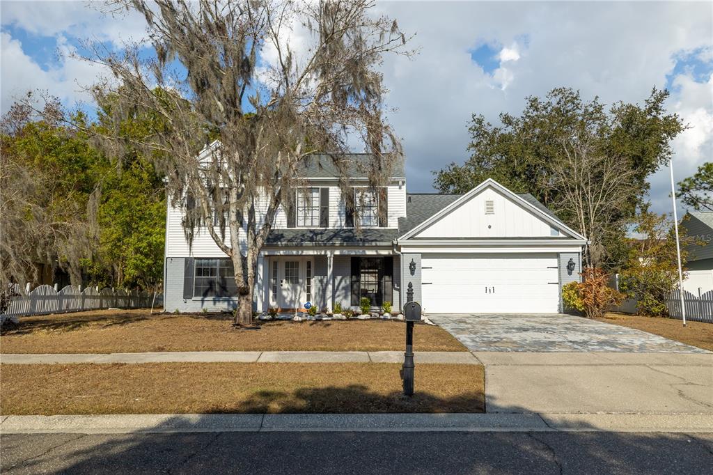 A two-story house with a white garage, gray brick lower level, and a large oak tree — 3728 MURRAY DALE DRIVE, VALRICO, FL