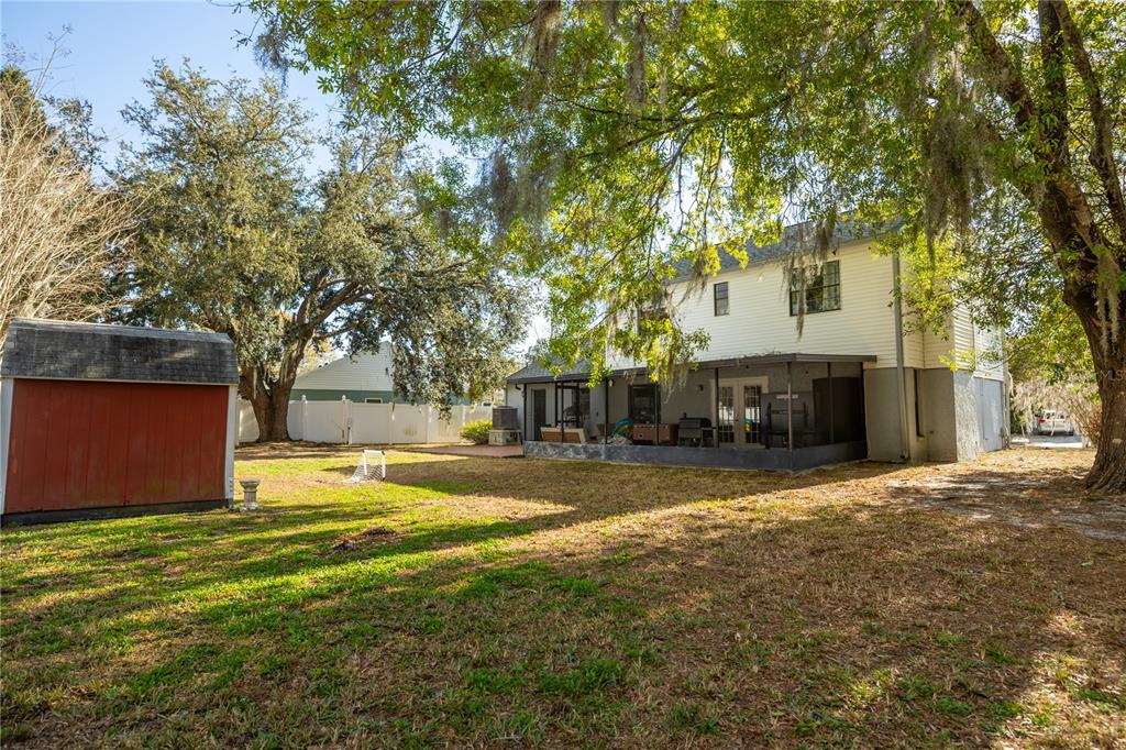 A backyard view of a two-story house with a screened porch and a red shed — 3728 MURRAY DALE DRIVE, VALRICO, FL