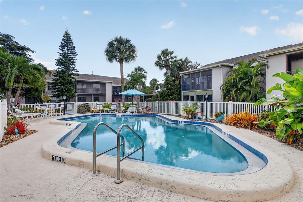 A swimming pool with a metal ladder sits in a courtyard surrounded by apartment buildings — 6146 7TH AVENUE W UNIT 6146, BRADENTON, FL