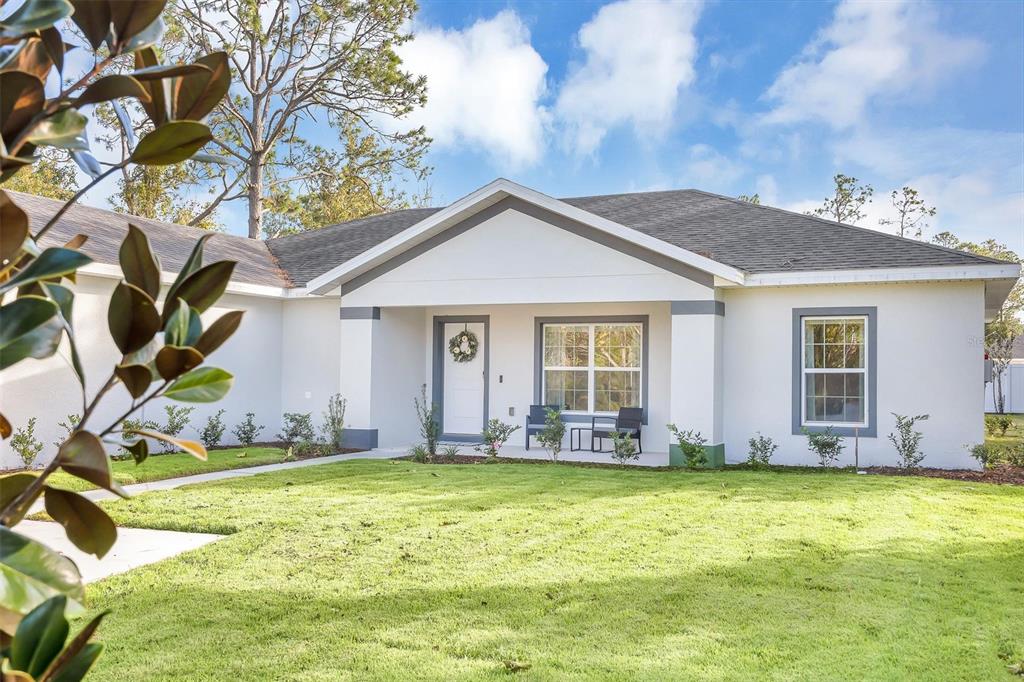 A single-story house with a white exterior, gray trim, and a front lawn — 56 WHITE FEATHER LANE, PALM COAST, FL