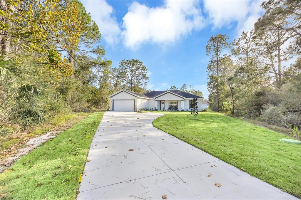 A single-story house with a white exterior, a two-car garage, and a long concrete driveway — 56 WHITE FEATHER LANE, PALM COAST, FL