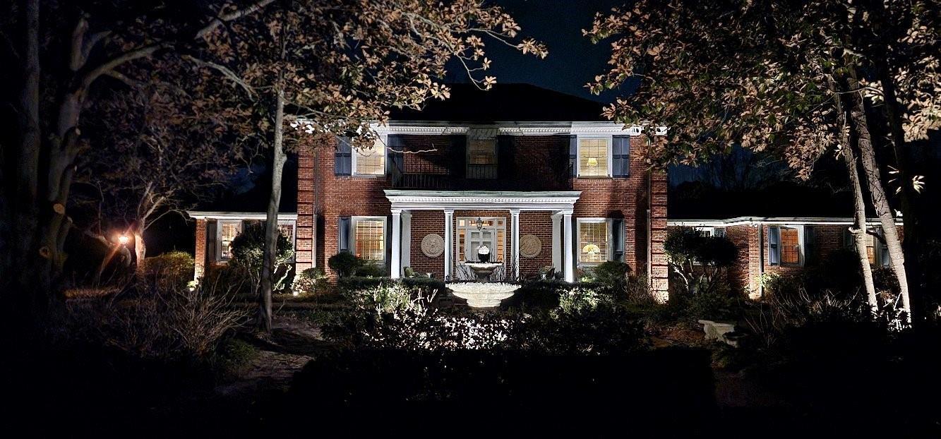 A two-story brick house at night with illuminated landscaping, a central fountain, and exterior lighting — 310 Woodland Drive, NC, NC