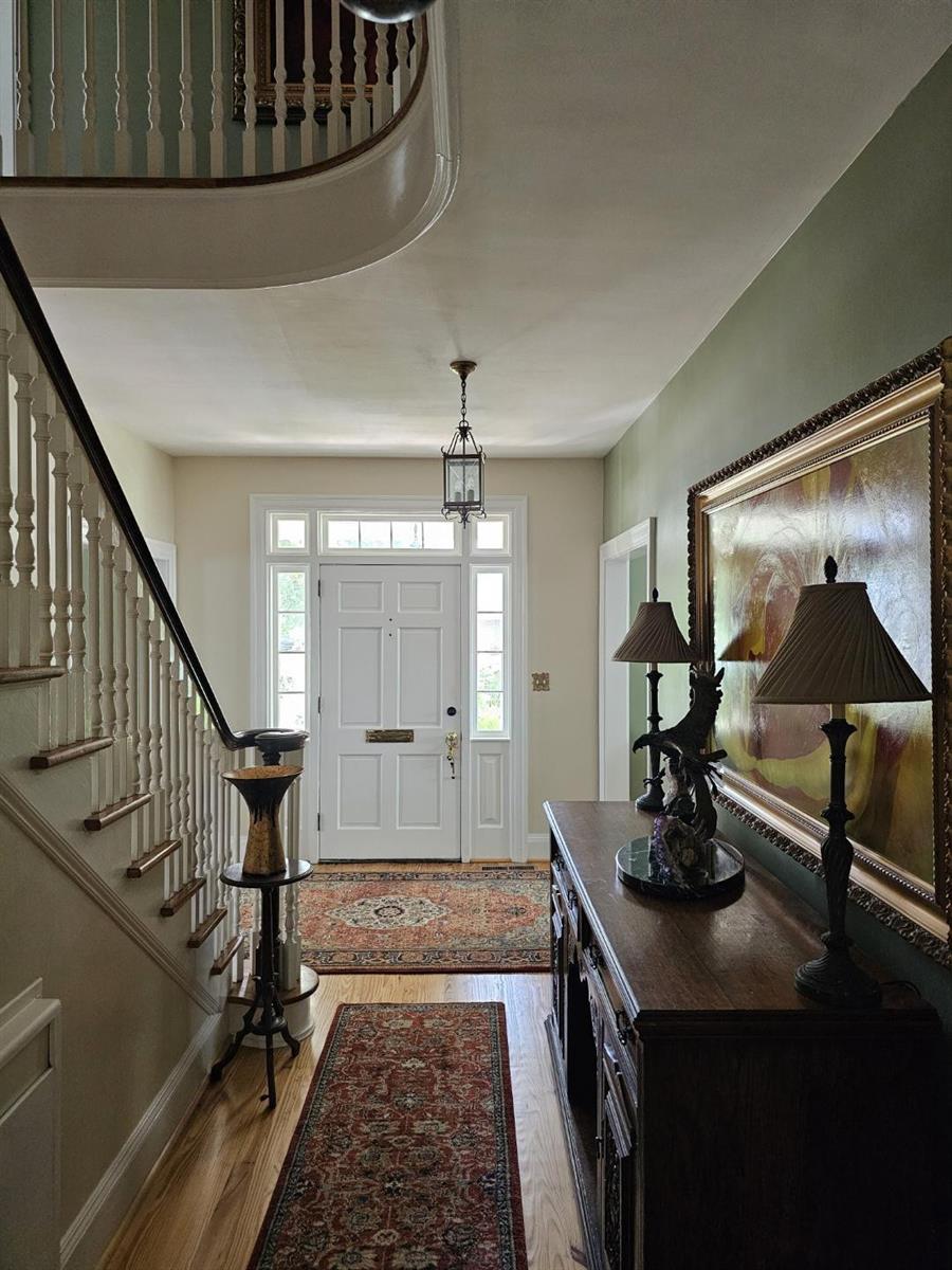 A foyer features a wooden staircase, a console table with lamps, and patterned area rugs — 310 Woodland Drive, NC, NC