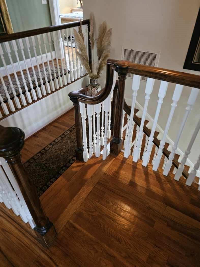 A wooden staircase features white balusters and a dark stained handrail on a landing — 310 Woodland Drive, NC, NC