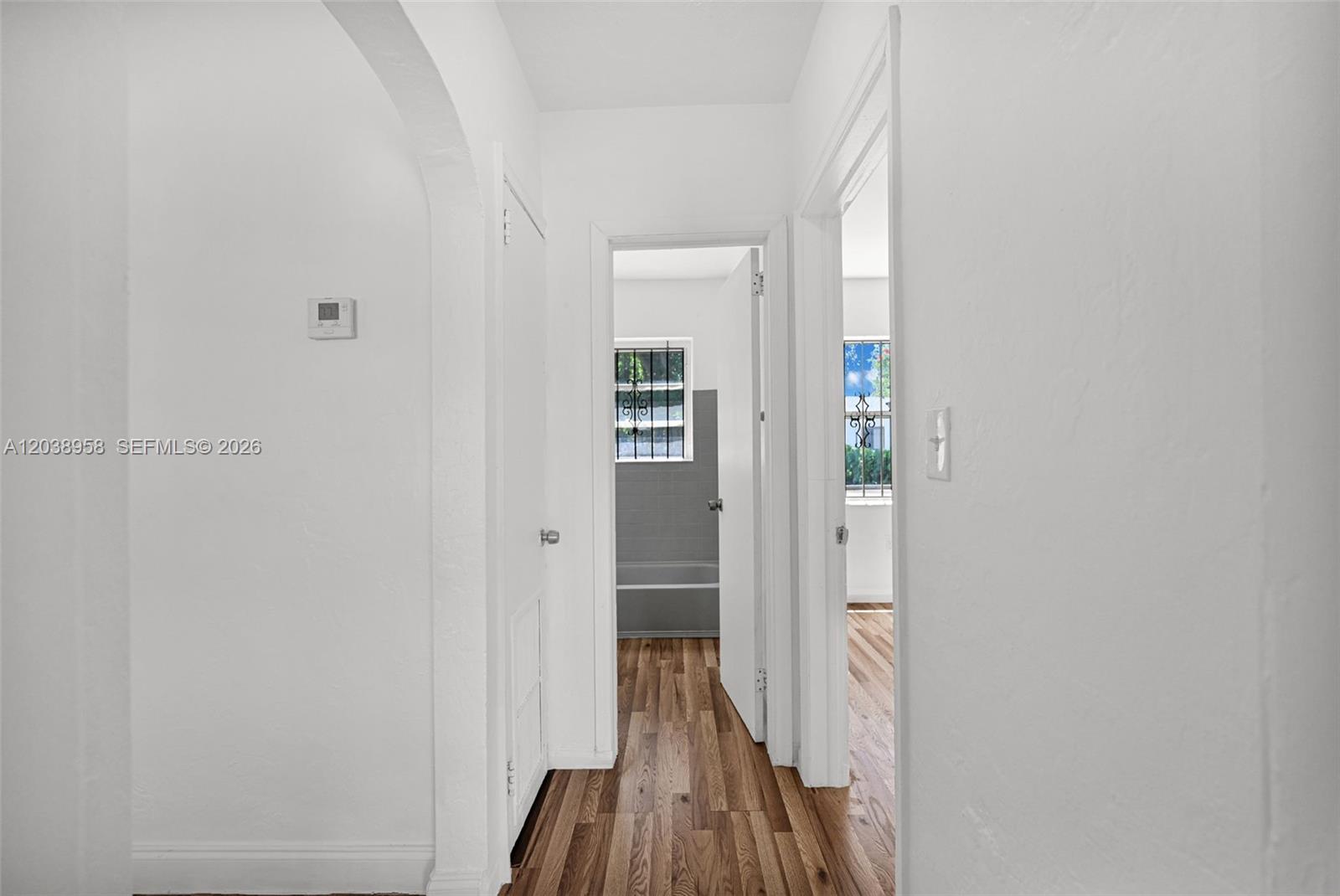 A hallway with white walls and wood-look flooring leads to a bathroom and bedroom — 5511 NW 12th Ave, Miami FL 33127, MIAMI, FL