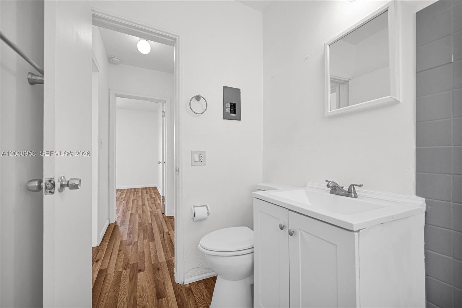 A small bathroom features a white vanity, a toilet, and a doorway leading to a hallway — 5511 NW 12th Ave, Miami FL 33127, MIAMI, FL
