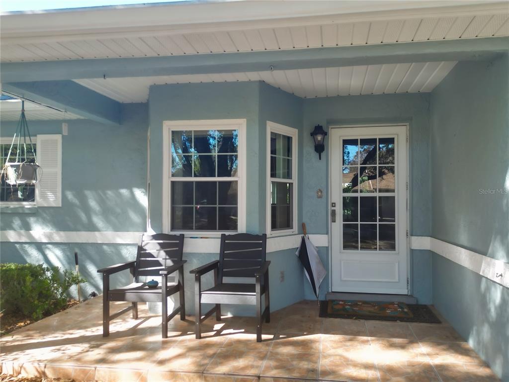 A covered front porch features tiled flooring, two dark chairs, and a white front door — 9330 SW 84TH TERRACE UNIT C, OCALA, FL