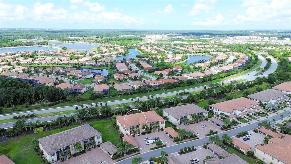 An aerial view shows a multi-story residential building circled within a suburban apartment complex — 13608 MESSINA LOOP UNIT 202, BRADENTON, FL
