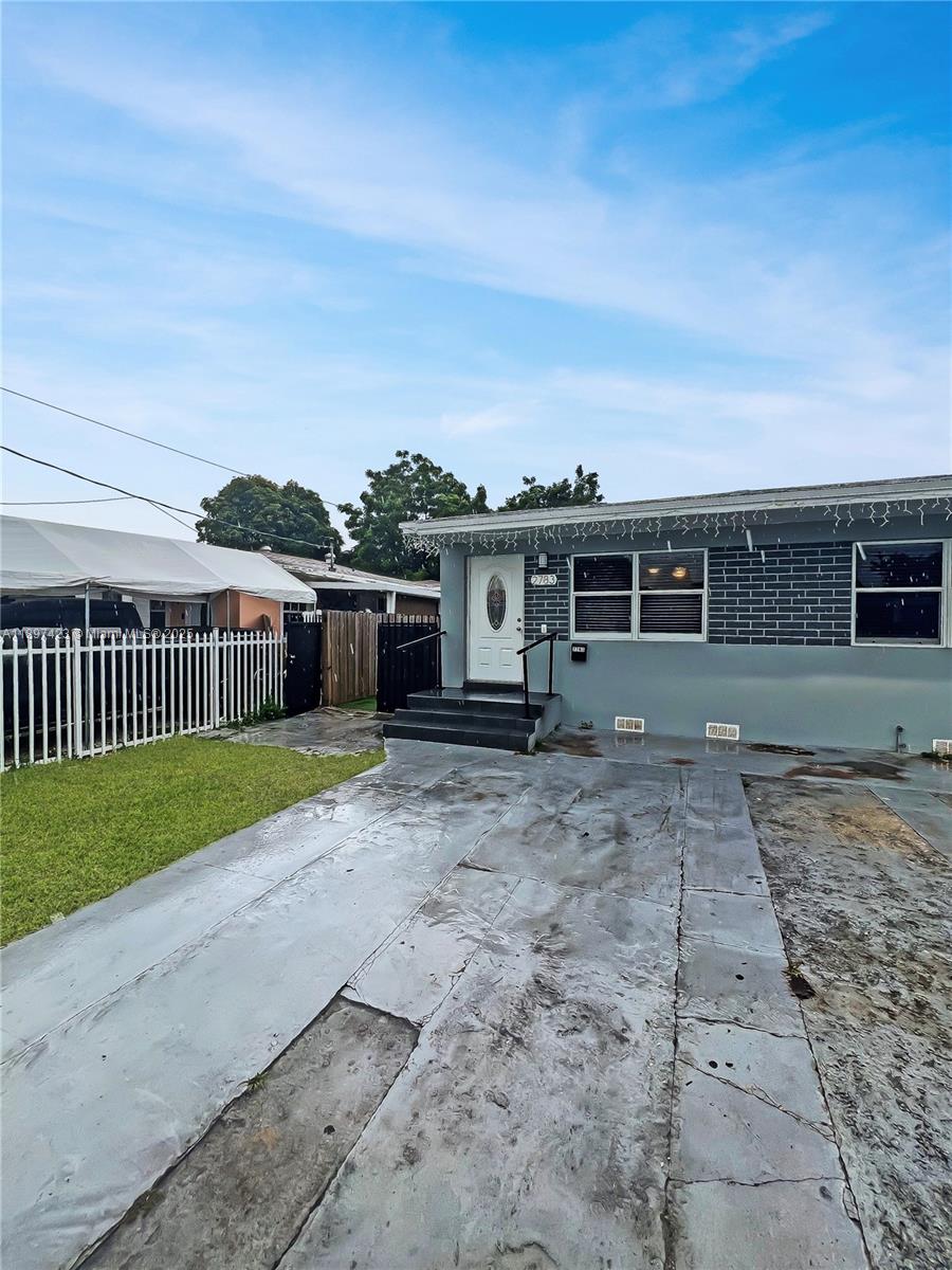 A single-story house features a gray brick facade, a white front door, and a concrete driveway — 2783 - 2785 SW 33rd Ct, Miami FL 33133, MIAMI, FL