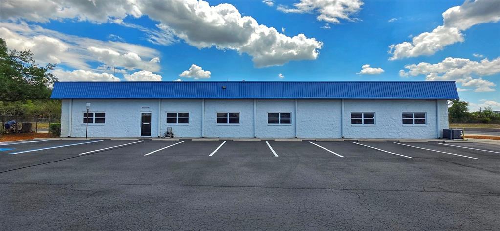 A single-story commercial building with a blue metal roof and a paved parking lot — 9324 EDEN AVENUE, HUDSON, FL