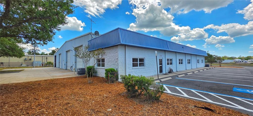 A single-story commercial building with a blue metal roof and white concrete block walls — 9324 EDEN AVENUE, HUDSON, FL