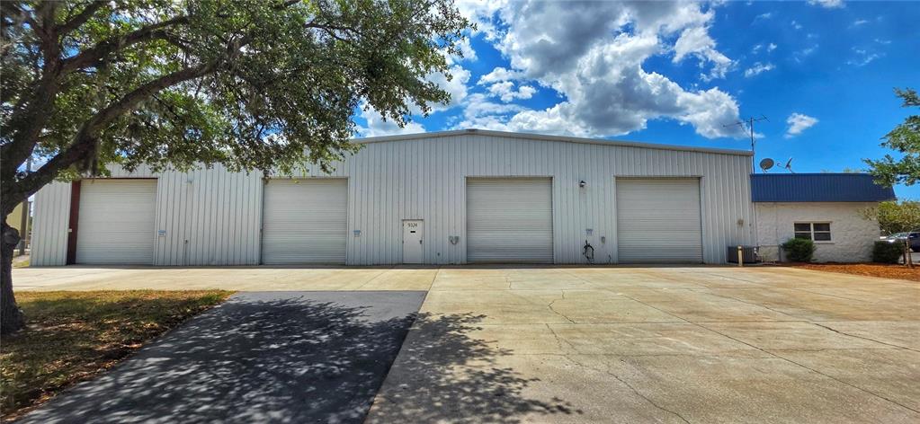 A single-story metal industrial building features four roll-up garage doors and a small attached office — 9324 EDEN AVENUE, HUDSON, FL