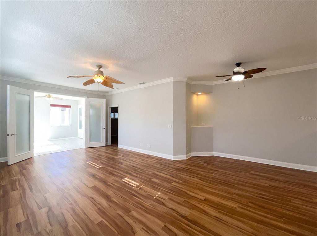 A spacious room features wood-look flooring, two ceiling fans, and a recessed wall niche — 5928 BRITTANIA BOULEVARD, TAVARES, FL