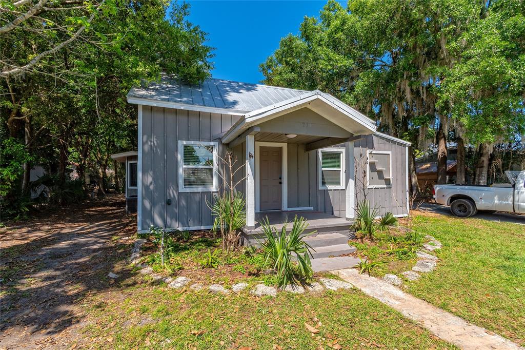 A small, gray, single-story house with a metal roof and a covered front porch — 714 WYOMING AVENUE, ST CLOUD, FL