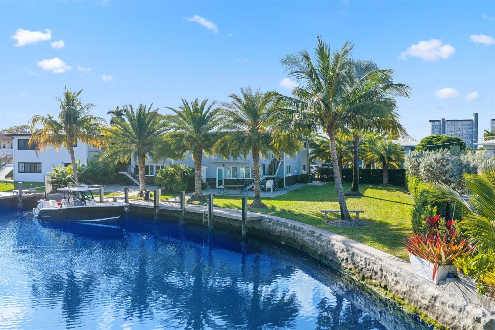 A boat is docked at a canal-front property with palm trees and a grassy lawn — 830 SE 22nd Avenue, Pompano Beach FL 33062, POMPANO BEACH, FL