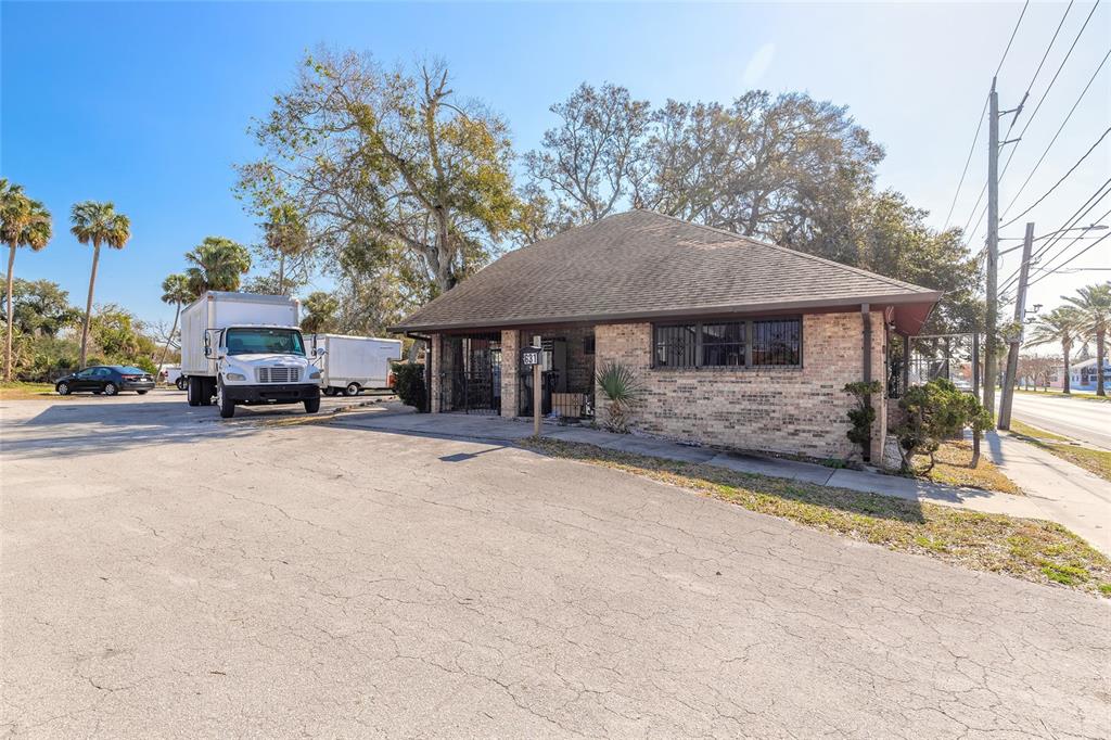 A single-story brick building with a hip roof sits on a paved lot with trucks — 631 N RIDGEWOOD AVENUE, DAYTONA BEACH, FL