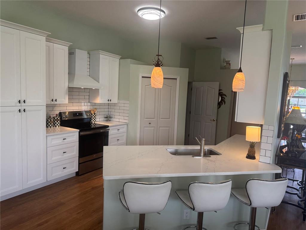 A kitchen with white cabinets, a quartz island, bar seating, and light green walls — 7102 42ND COURT E, SARASOTA, FL