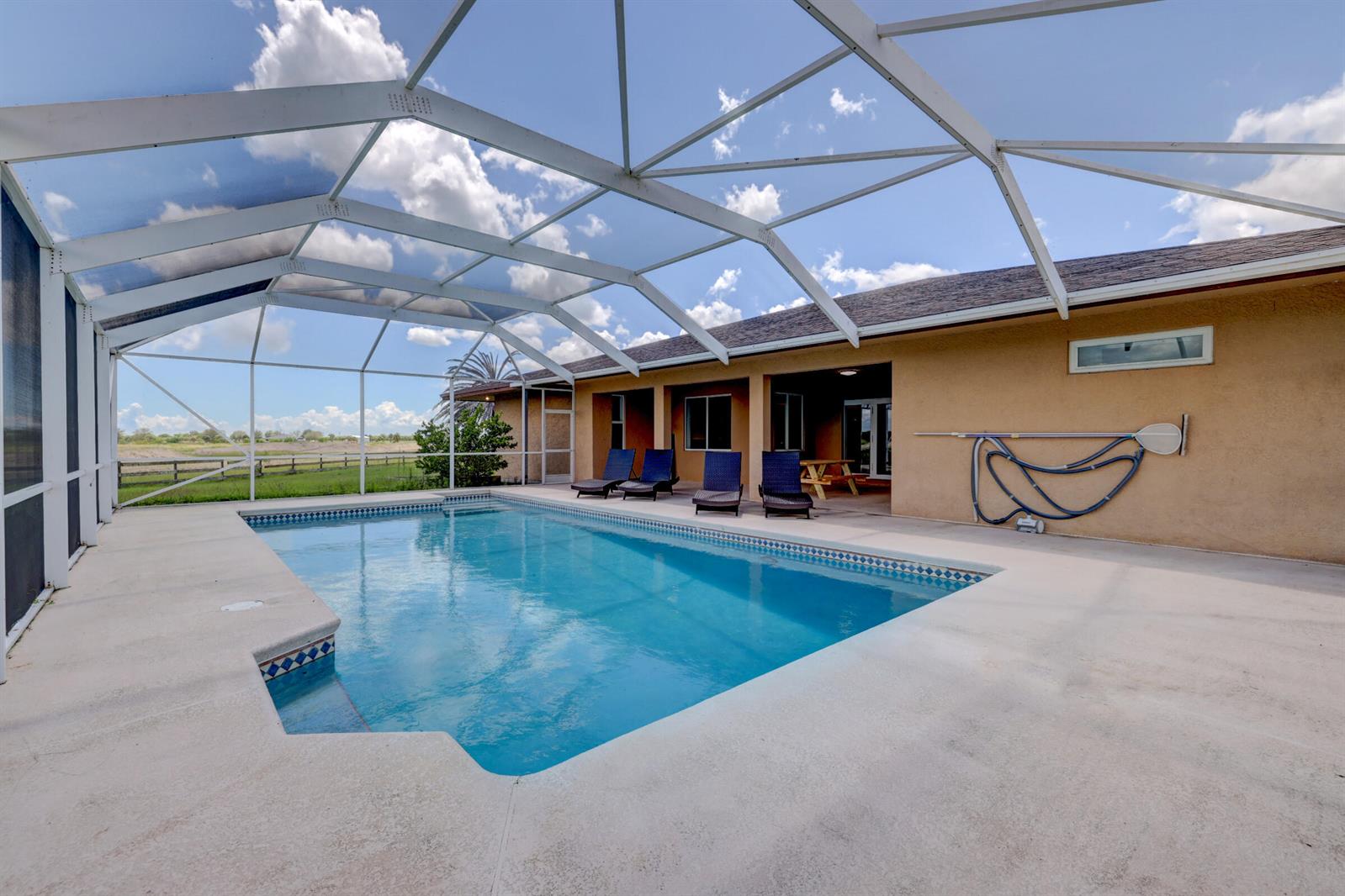 A screened-in patio features a rectangular swimming pool and four lounge chairs — 2700 S Header Canal Road, Fort Pierce FL 34945, FORT PIERCE, FL