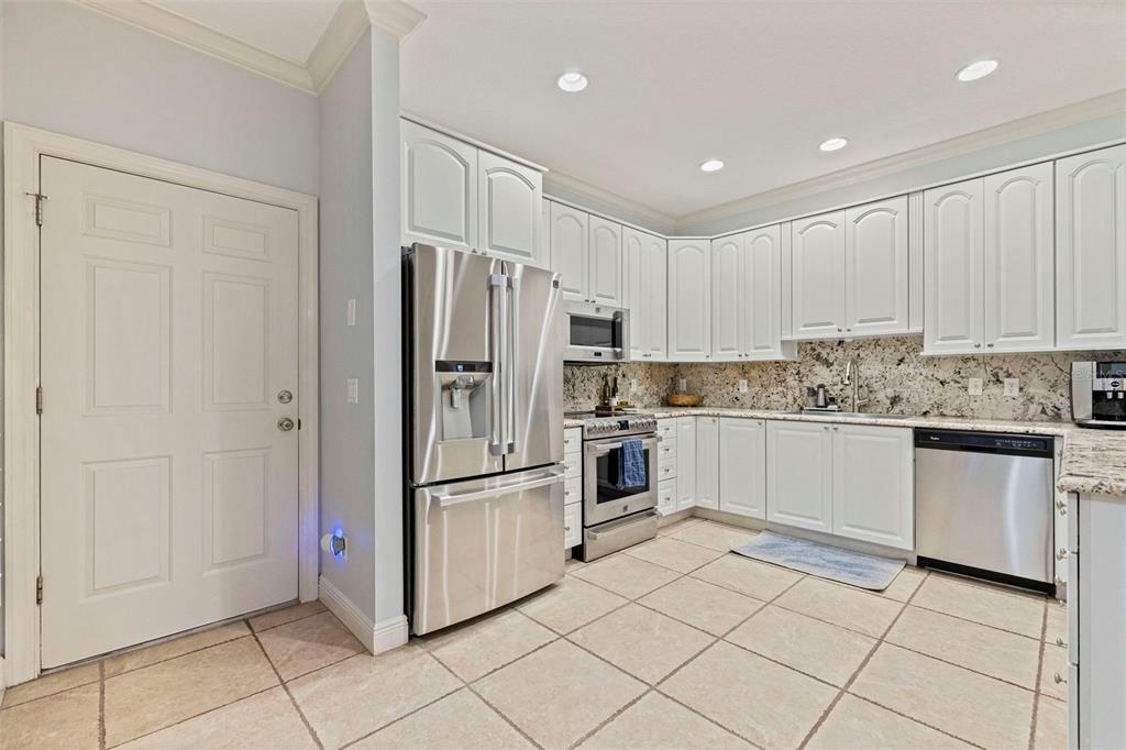A kitchen with white cabinets, stainless steel appliances, granite countertops, and light-colored tile flooring — 123 VALENCIA CIRCLE, ST PETERSBURG, FL