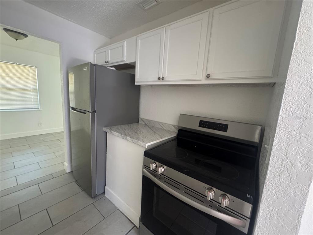 A kitchen features white cabinets, a stainless steel refrigerator, and a black electric range — 6619 S WEST SHORE BOULEVARD UNIT A, TAMPA, FL
