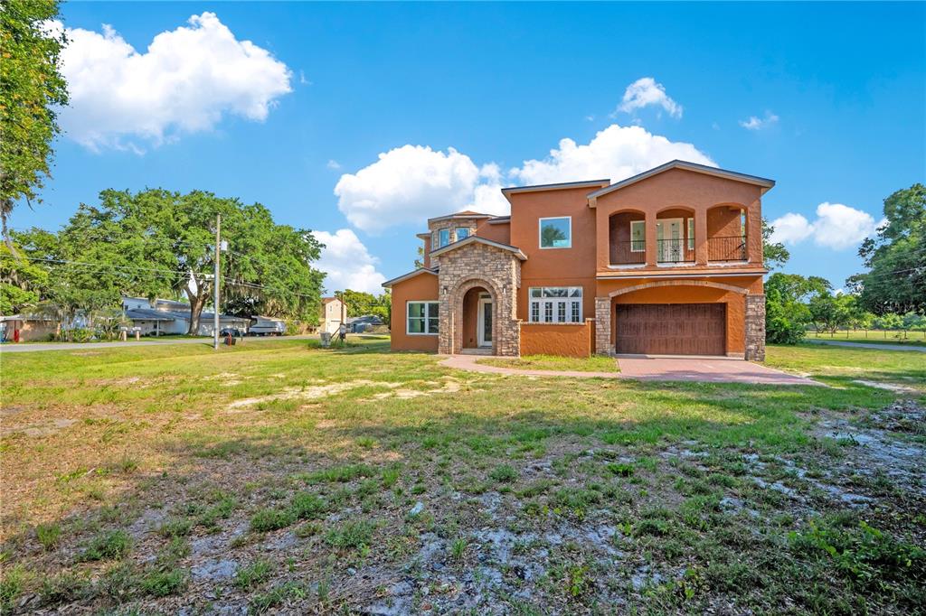 A two-story stucco house with a stone-accented entryway and an attached two-car garage — 818 LAKE AGNES DRIVE, POLK CITY, FL