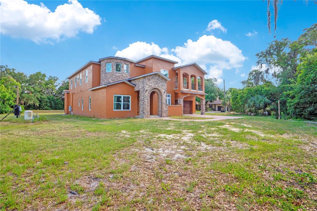 A two-story stucco and stone house with a front entrance and attached garage — 818 LAKE AGNES DRIVE, POLK CITY, FL