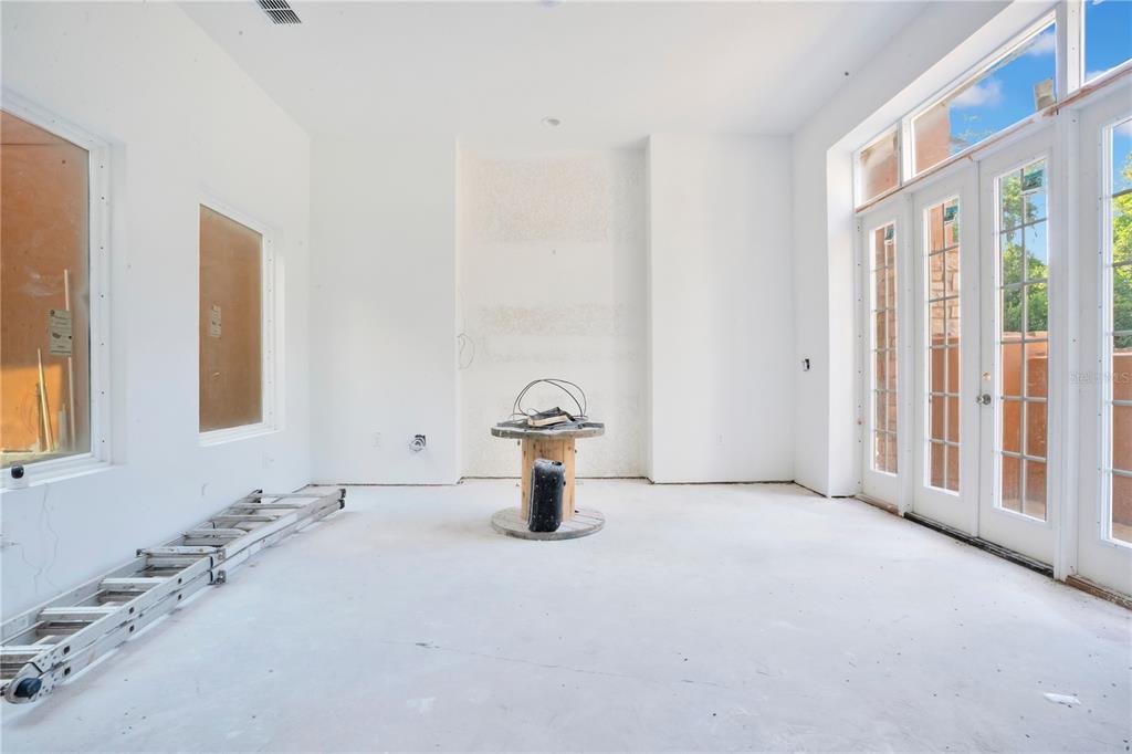 An unfinished room features white walls, a concrete floor, a wooden spool, and glass doors — 818 LAKE AGNES DRIVE, POLK CITY, FL