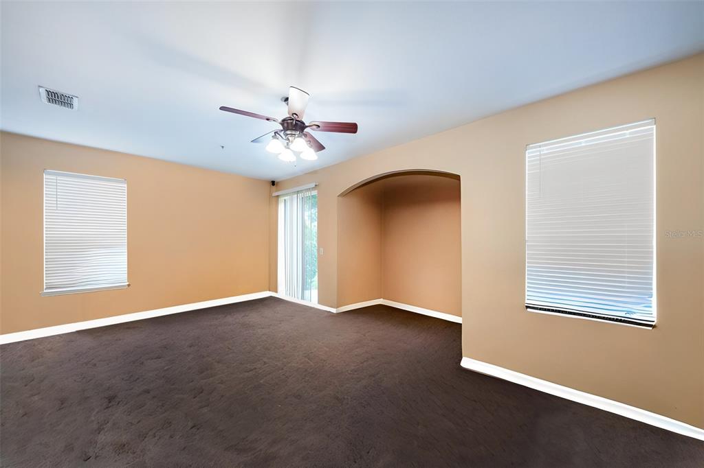An empty room features tan walls, dark carpeting, a ceiling fan, and two windows — 3221 SAN JACINTO CIRCLE UNIT 3221, SANFORD, FL