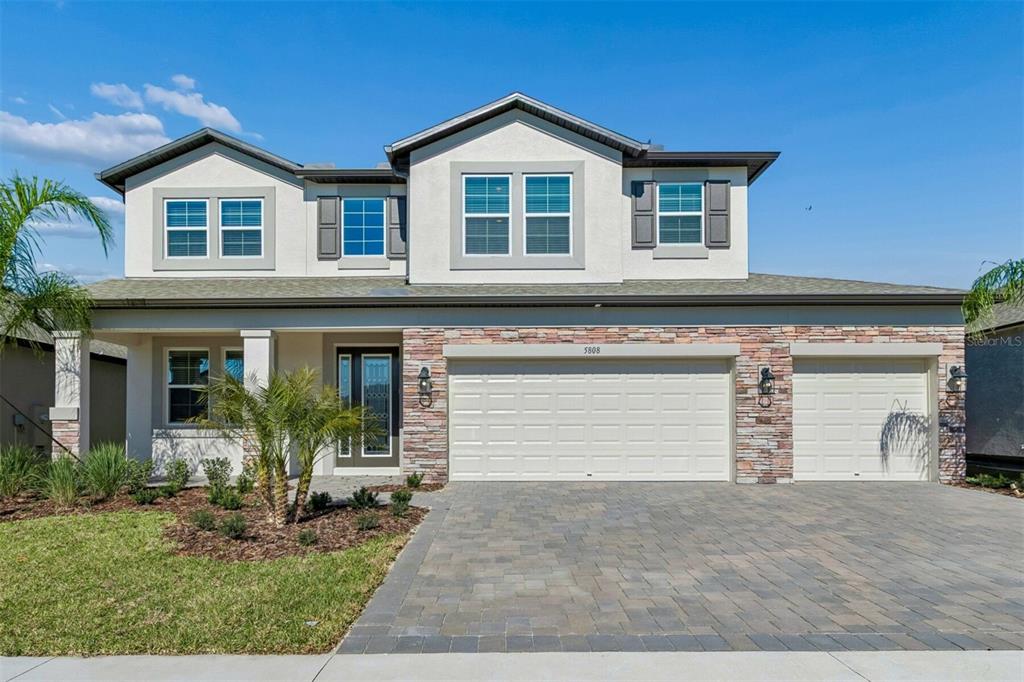 A two-story house with a stone-accented facade, a three-car garage, and a paved driveway — 5808 FREESIA DRIVE, LAKELAND, FL