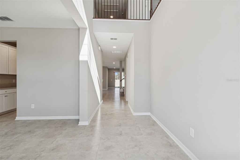 A view of a tiled hallway leading to an open living area with a staircase — 5808 FREESIA DRIVE, LAKELAND, FL