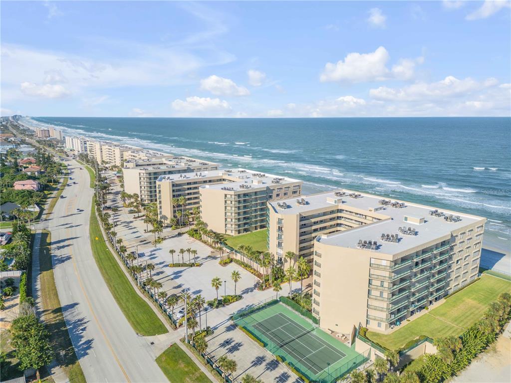 An aerial view of a beachfront condominium complex with a tennis court and parking lot — 4575 S ATLANTIC AVENUE UNIT 6402, PONCE INLET, FL