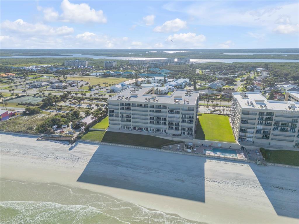 An aerial view of a beachfront condominium building with a pool and sandy beach — 4575 S ATLANTIC AVENUE UNIT 6402, PONCE INLET, FL