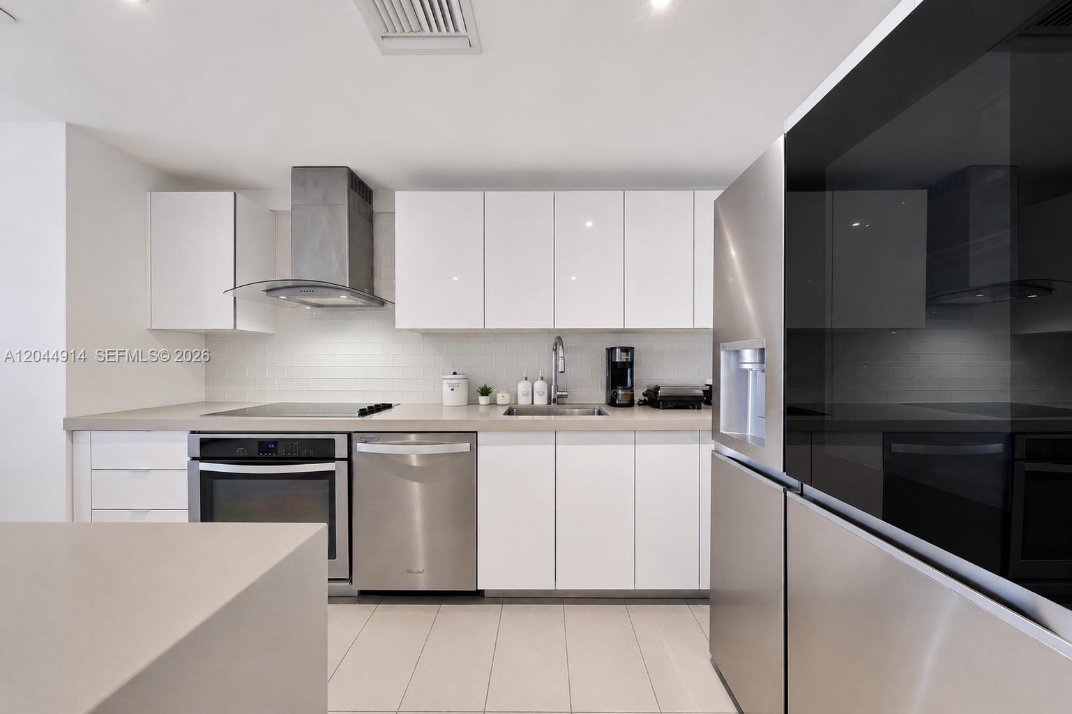 A modern kitchen features white cabinets, stainless steel appliances, and a subway tile backsplash — 1600 NE 1st Ave # 2814, Miami FL 33132, MIAMI, FL