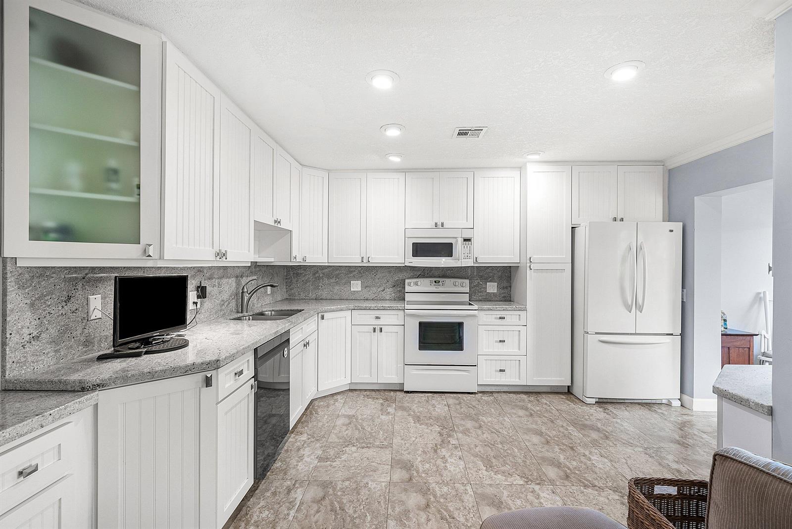 A kitchen with white cabinets, granite countertops, stainless steel appliances, and tile flooring — 11212 Quail Covey Road, Boynton Beach FL 33436, BOYNTON BEACH, FL