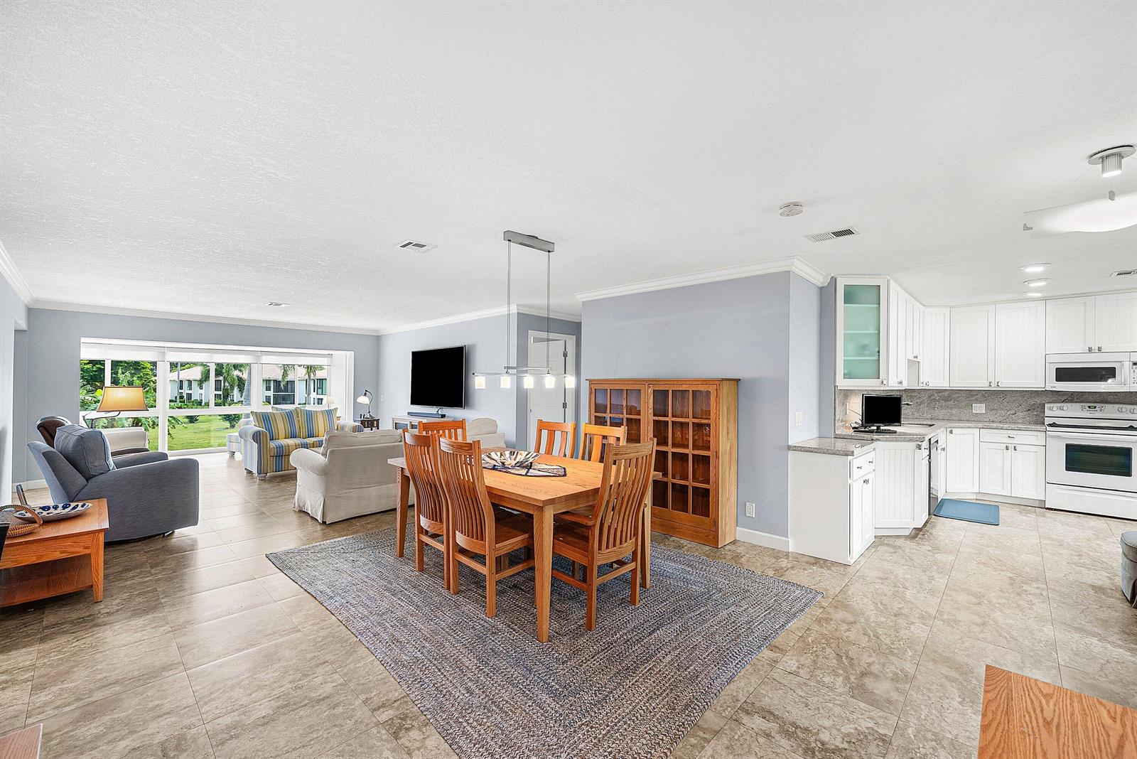 An open-concept living and dining area features tile flooring, a wooden dining set, and kitchen — 11212 Quail Covey Road, Boynton Beach FL 33436, BOYNTON BEACH, FL