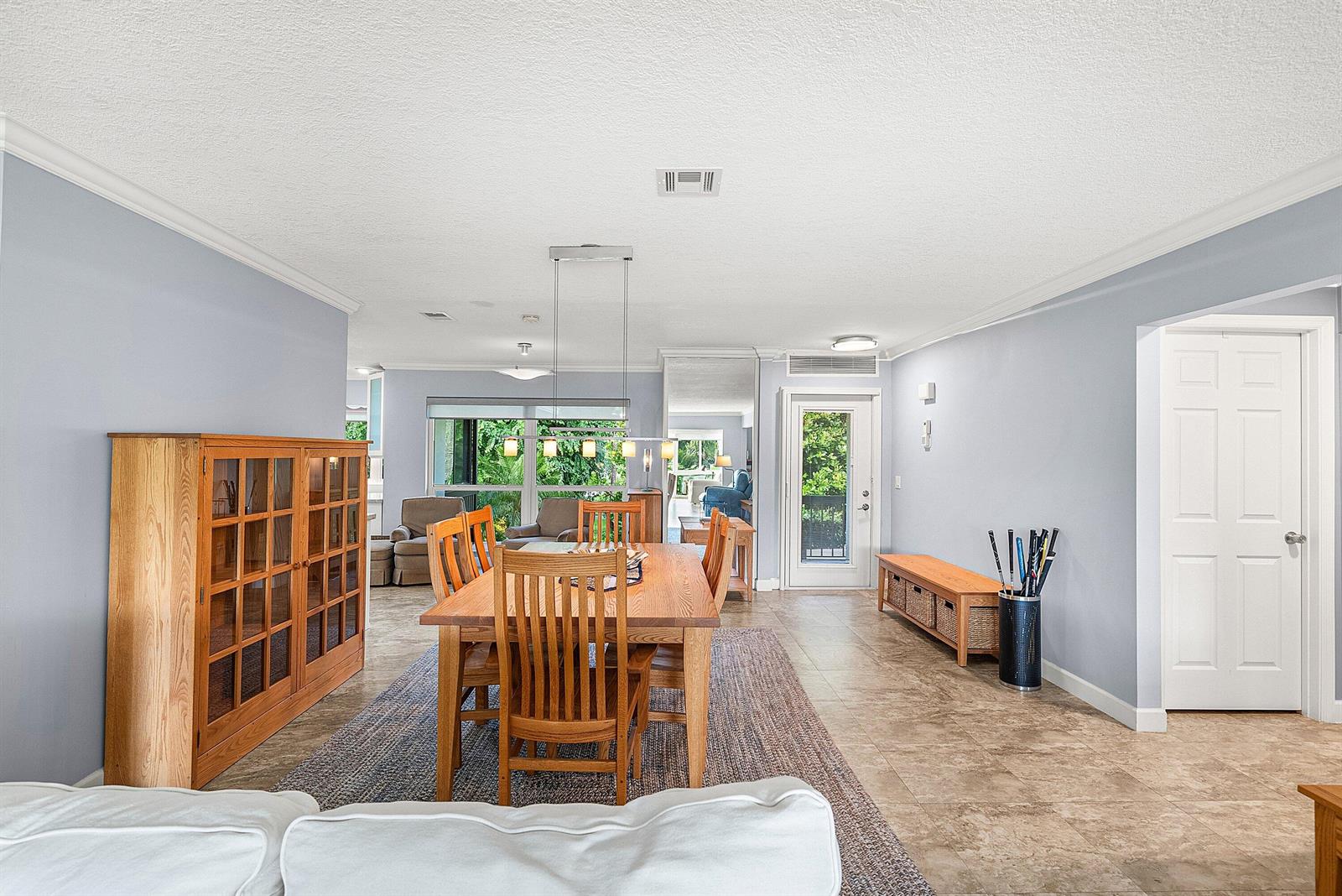 A dining area with a wooden table and chairs sits on a rug near a living space — 11212 Quail Covey Road, Boynton Beach FL 33436, BOYNTON BEACH, FL