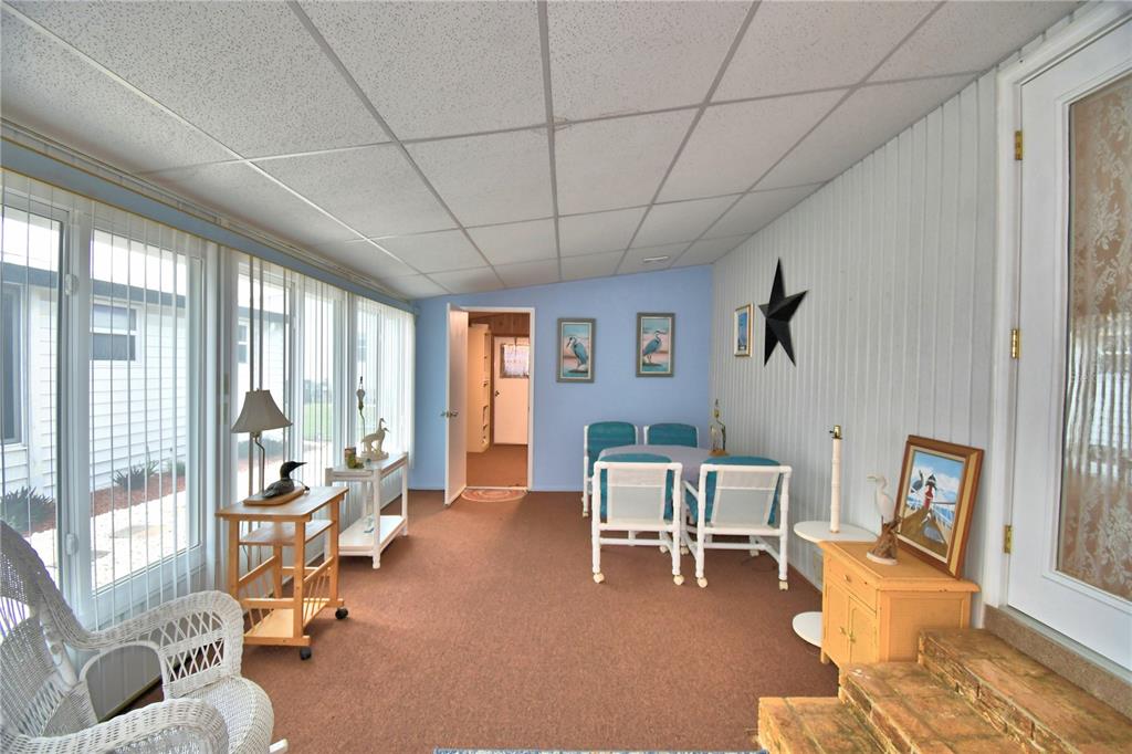 A sunroom features brown carpeting, a drop ceiling, blue walls, and a small dining set — 4146 SPRUCEWOOD STREET, WINTER HAVEN, FL