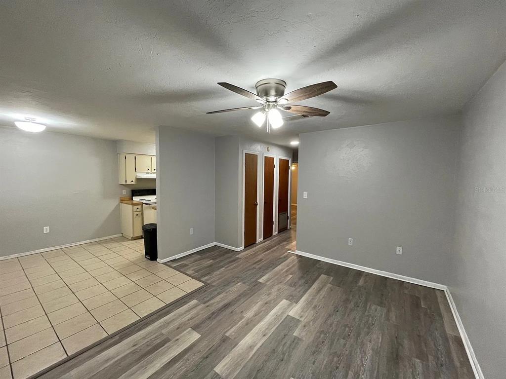 An open-concept living area features wood-look flooring, a ceiling fan, and an adjacent tiled kitchen — 2210 SW 70TH TERRACE, GAINESVILLE, FL