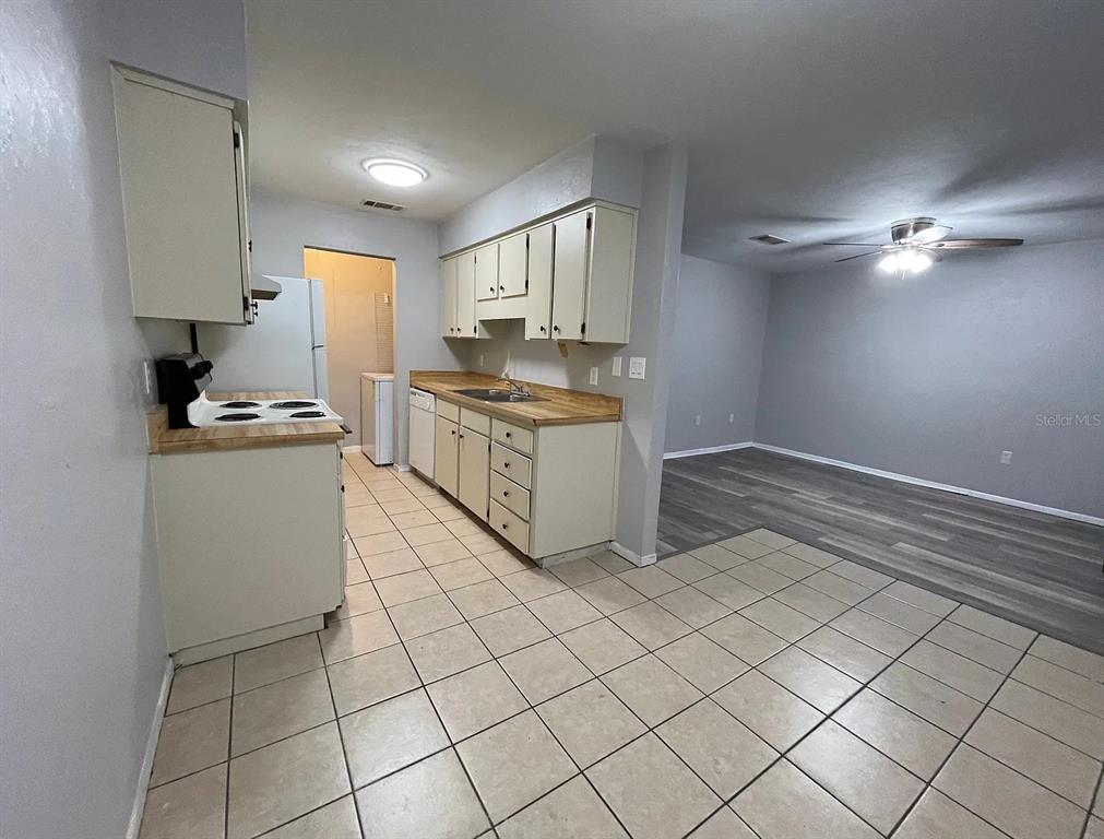 A kitchen with light-colored cabinets and tile flooring opens into a gray-walled living area — 2210 SW 70TH TERRACE, GAINESVILLE, FL