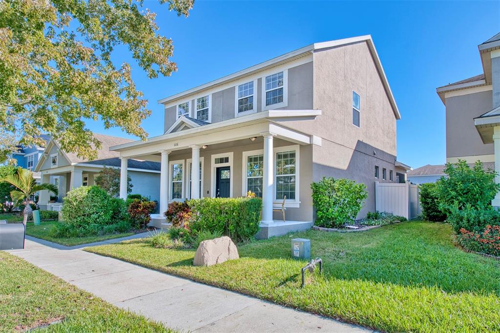 A two-story house with a front porch, gray siding, and a landscaped front yard — 606 LAKE TALQUIN WAY, GROVELAND, FL