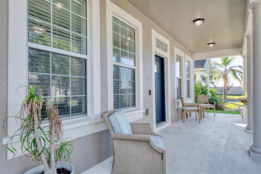 A covered front porch features a blue door, wicker chairs, and large windows — 606 LAKE TALQUIN WAY, GROVELAND, FL
