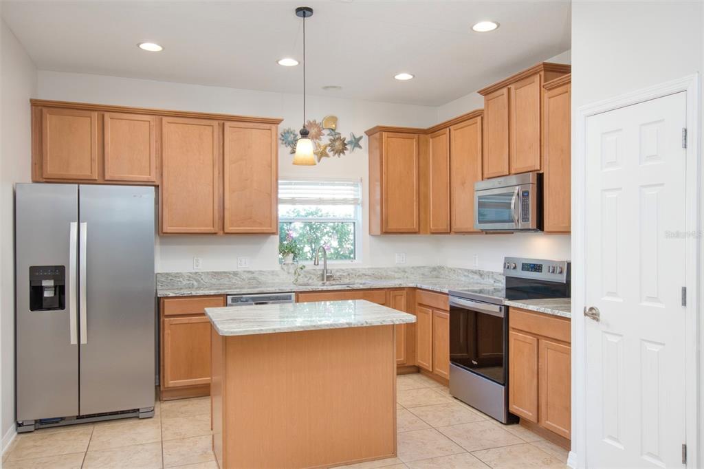 A kitchen with light wood cabinets, stainless steel appliances, and a central island with countertops — 606 LAKE TALQUIN WAY, GROVELAND, FL